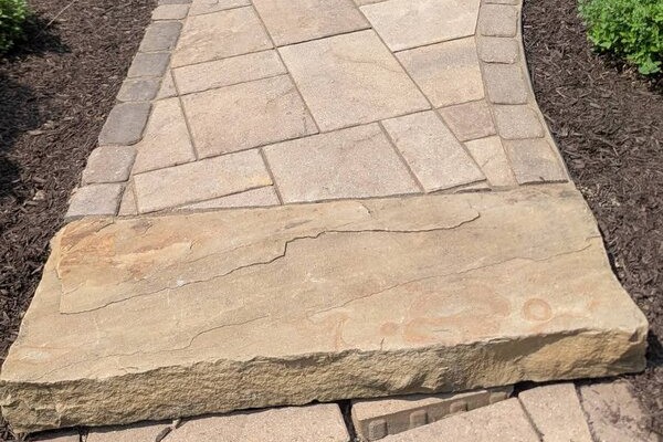 Stone step and paver walkway leading to a patio