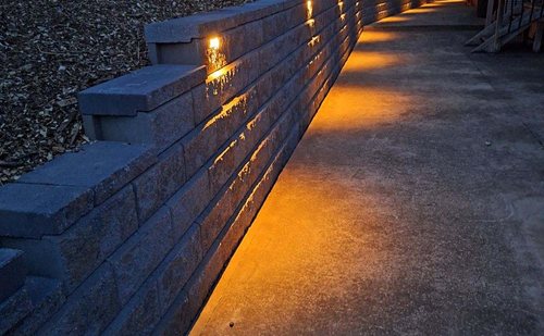 Retaining wall with landscape lighting along a walkway